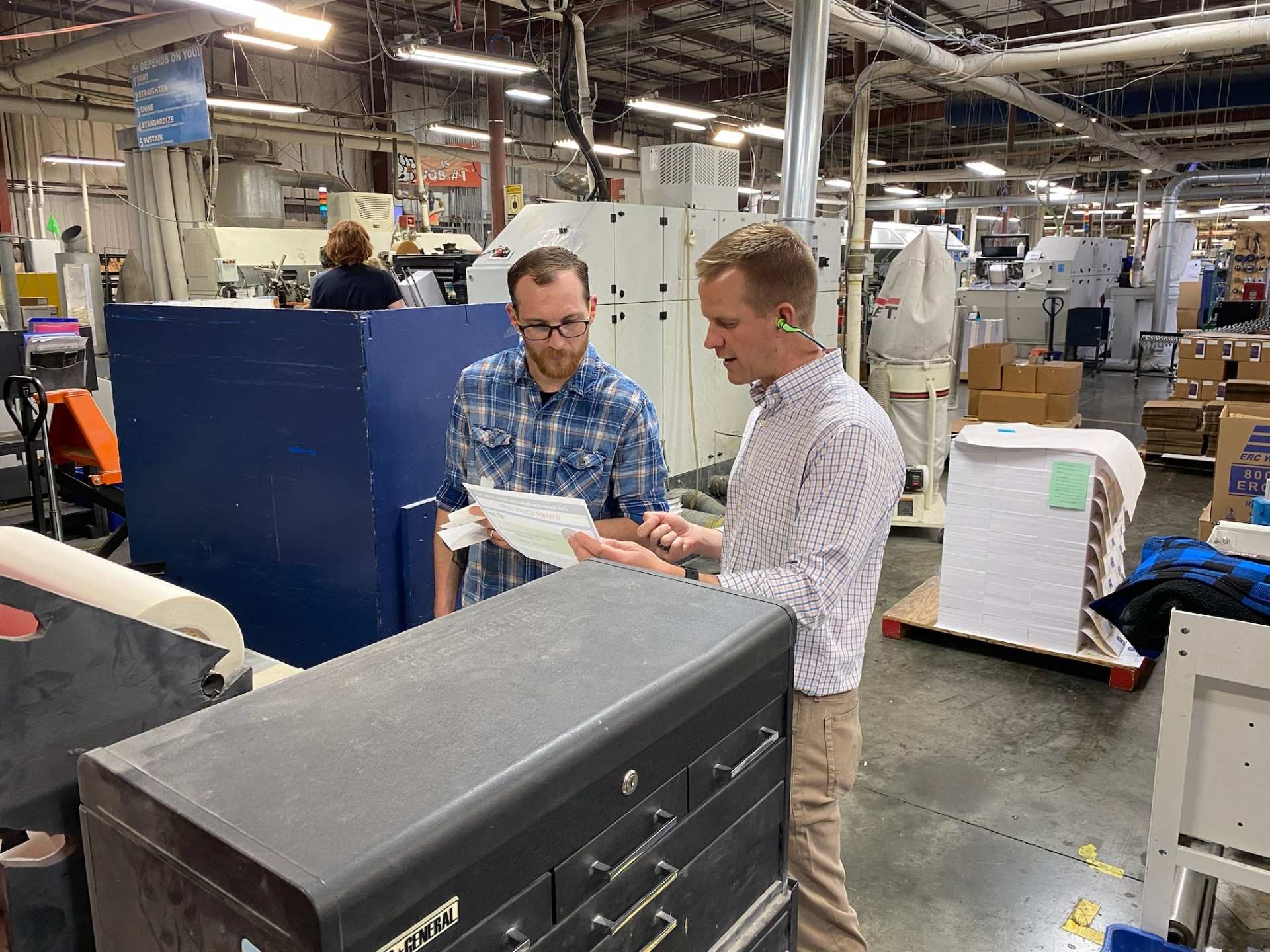 JBM CEO Marcus Sheanshang and an employee examine a piece of paper in the JBM packaging facility.