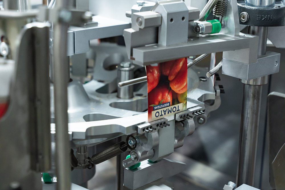 Atomated seed filling machine holding a seed packet for beefsteak tomatoes.