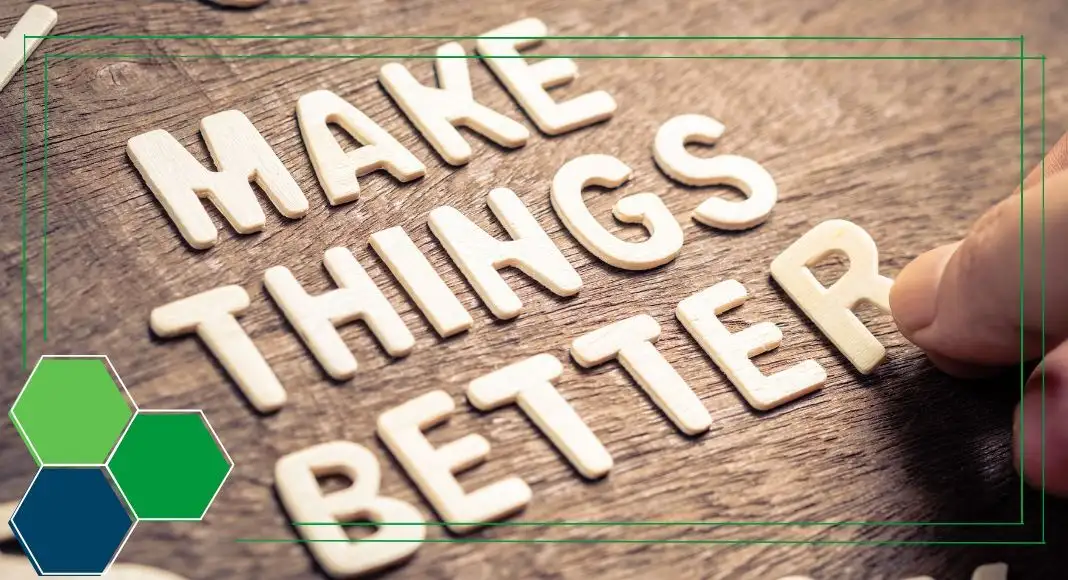 Close-up of hand placing white letters on wooden surface spelling: "Make things better."