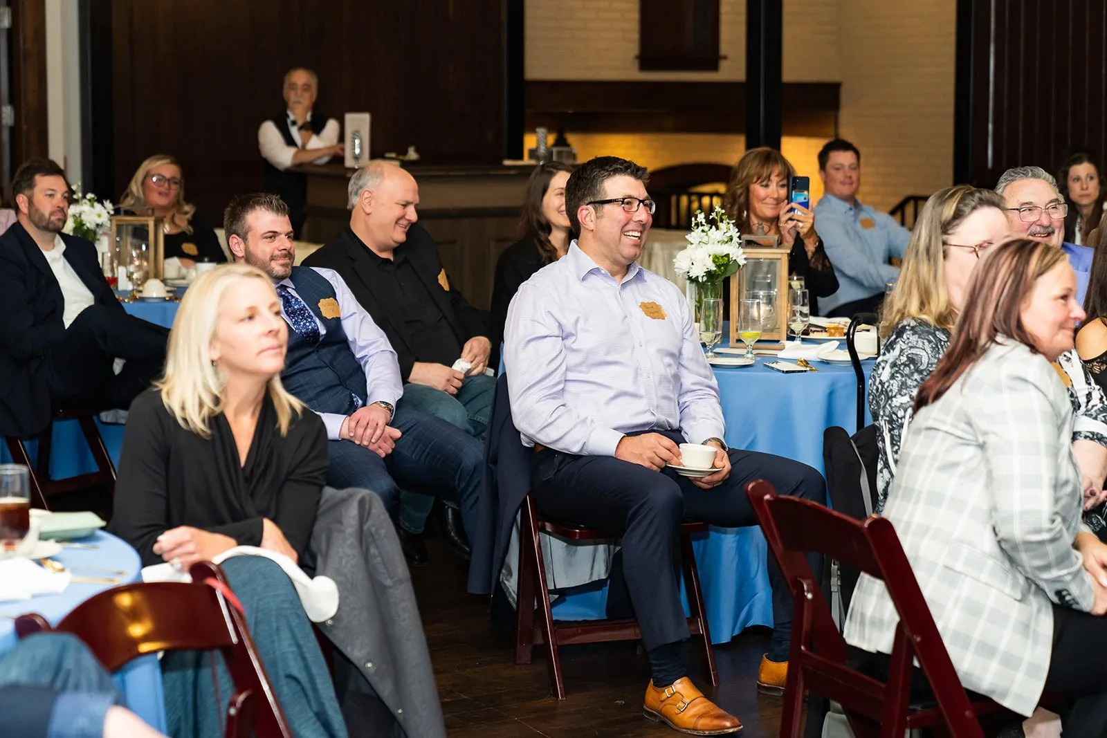 Individuals sitting at banquet tables looking forward, smiling.