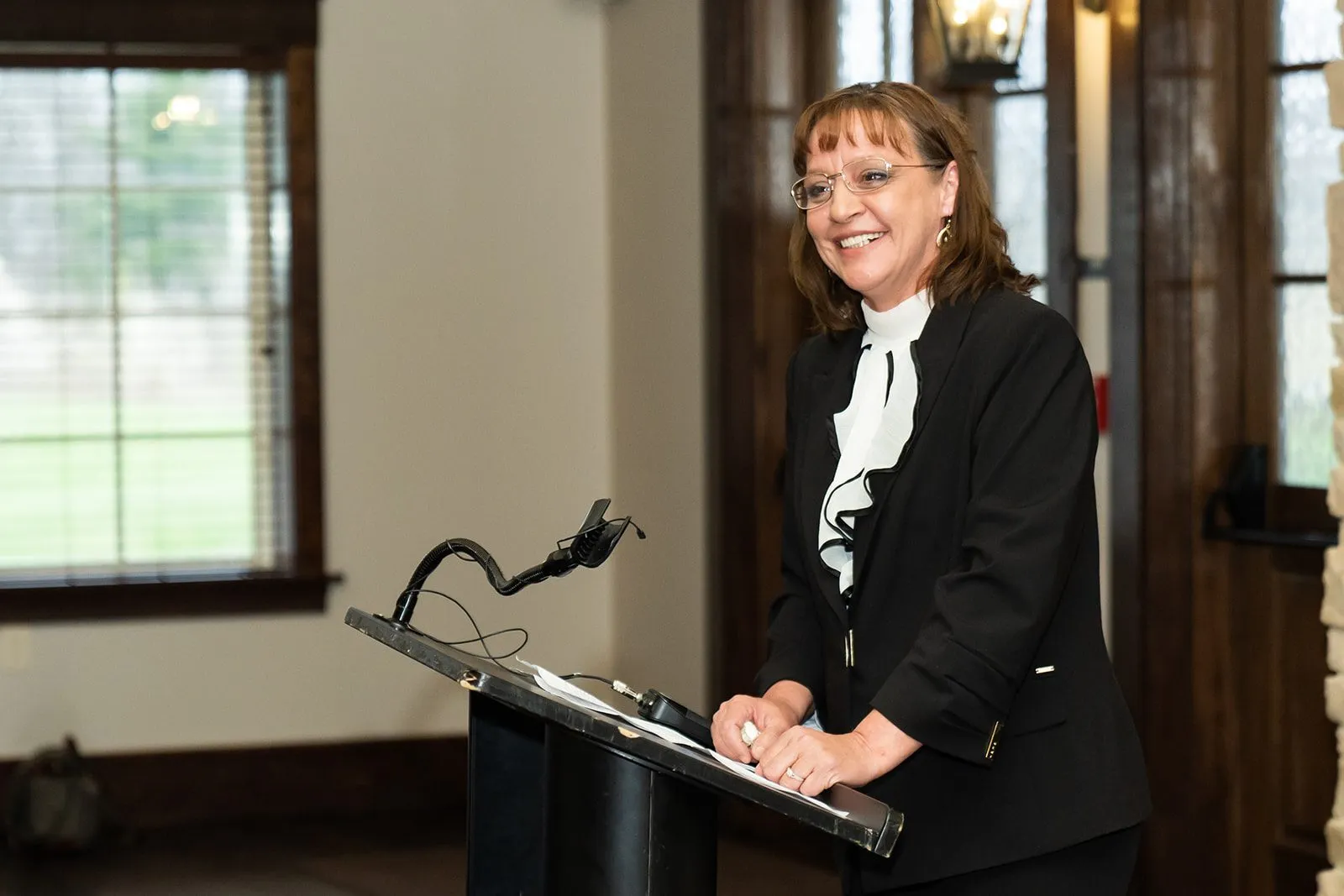 Woman smiling, presenting at a podium.