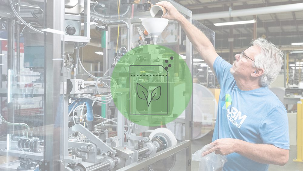 Man pouring a cup of seeds into a machine that fills seed pouches, overlaid with a blurred sheen. At the center of the image is a circular, green icon of a cartoon seed packet.