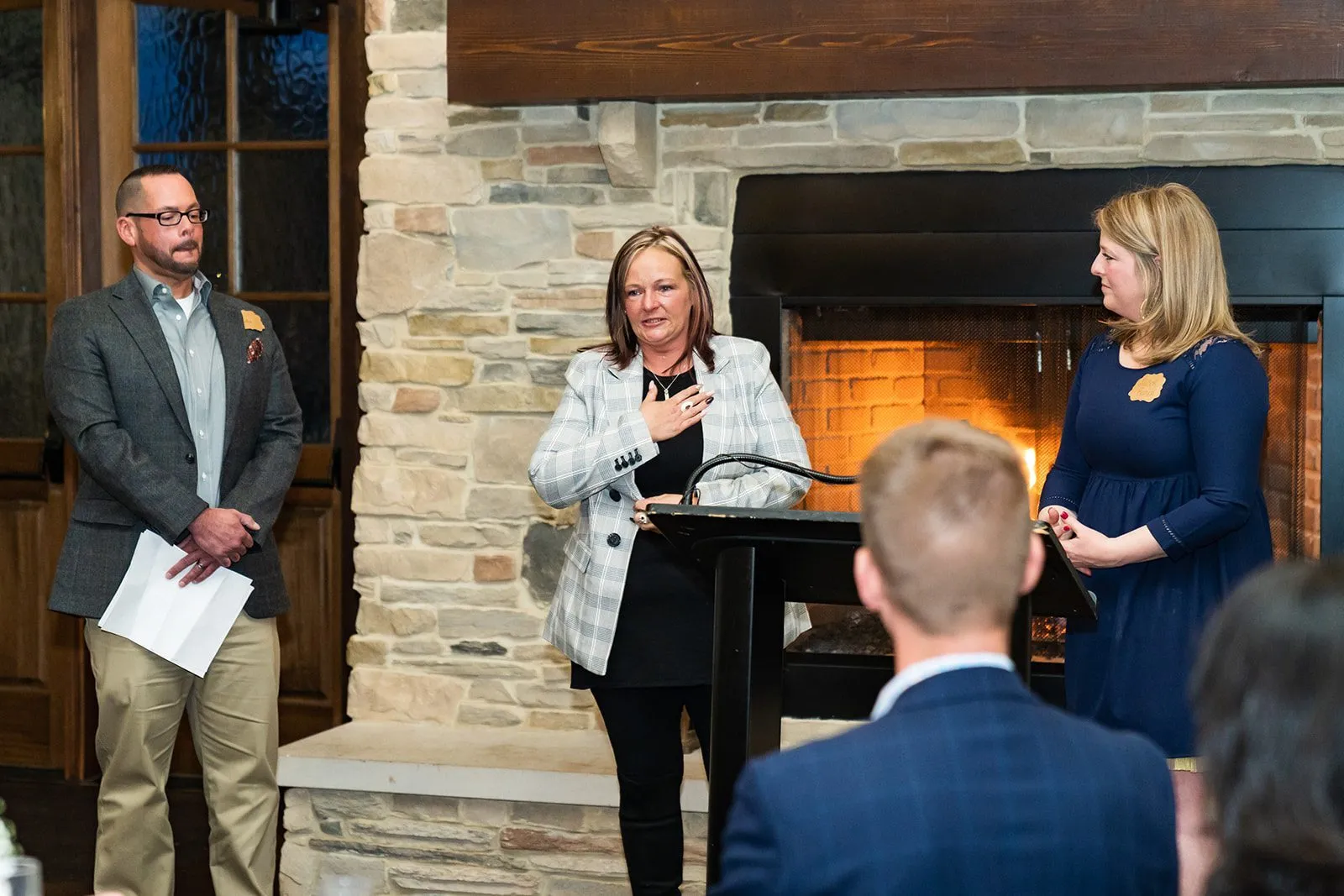 Woman speaking in front of room while others watch her from the side.