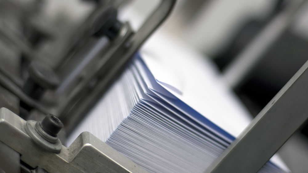 Close-up of a paper envelope stack on an industrial machine.